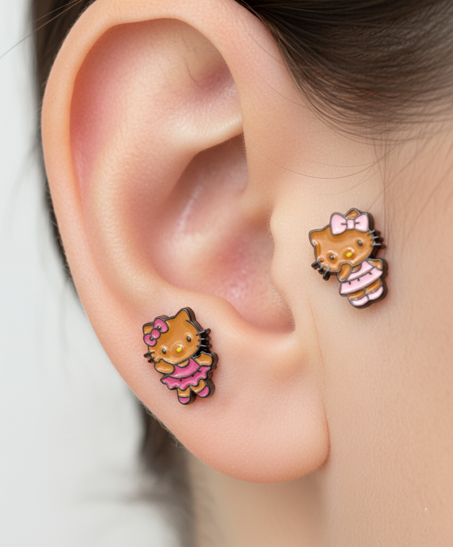 Adorable Hello Kitty–inspired piercing featuring a playful Hawaii-style cat in pink or red dress. Made with hypoallergenic surgical steel. Sold as single.