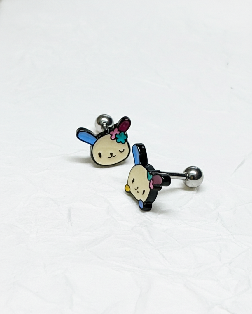 two Ussahana-inspired pastel bunny-face barbell studs placed on crumpled white paper, surgical steel posts visible