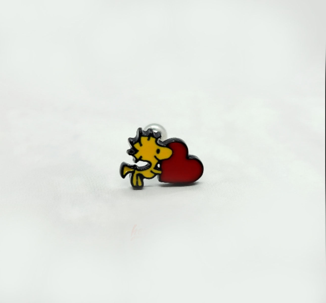 Solo Woodstock enamel earring hugging a red heart, placed on white background.