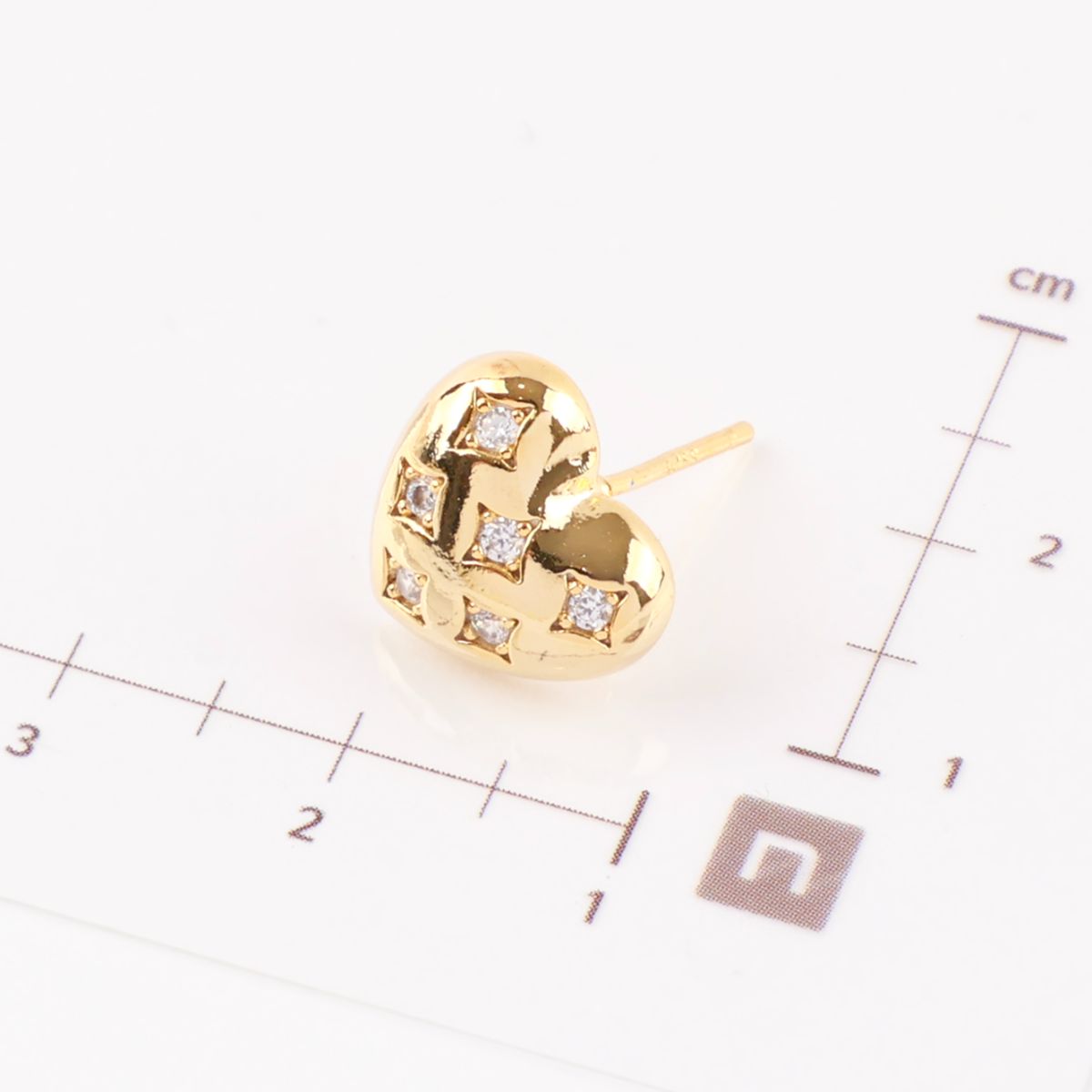 Size comparison of gold quilted heart earrings showing 1cm dimensions next to ruler
