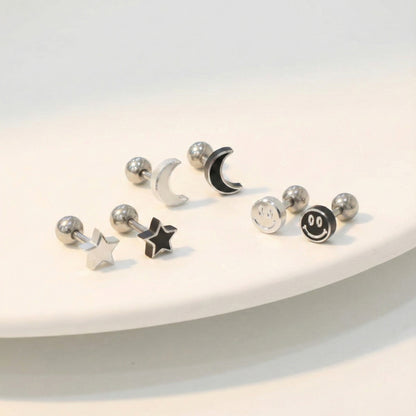 Surgical steel moon star smiley face piercing studs in silver and black on white surface