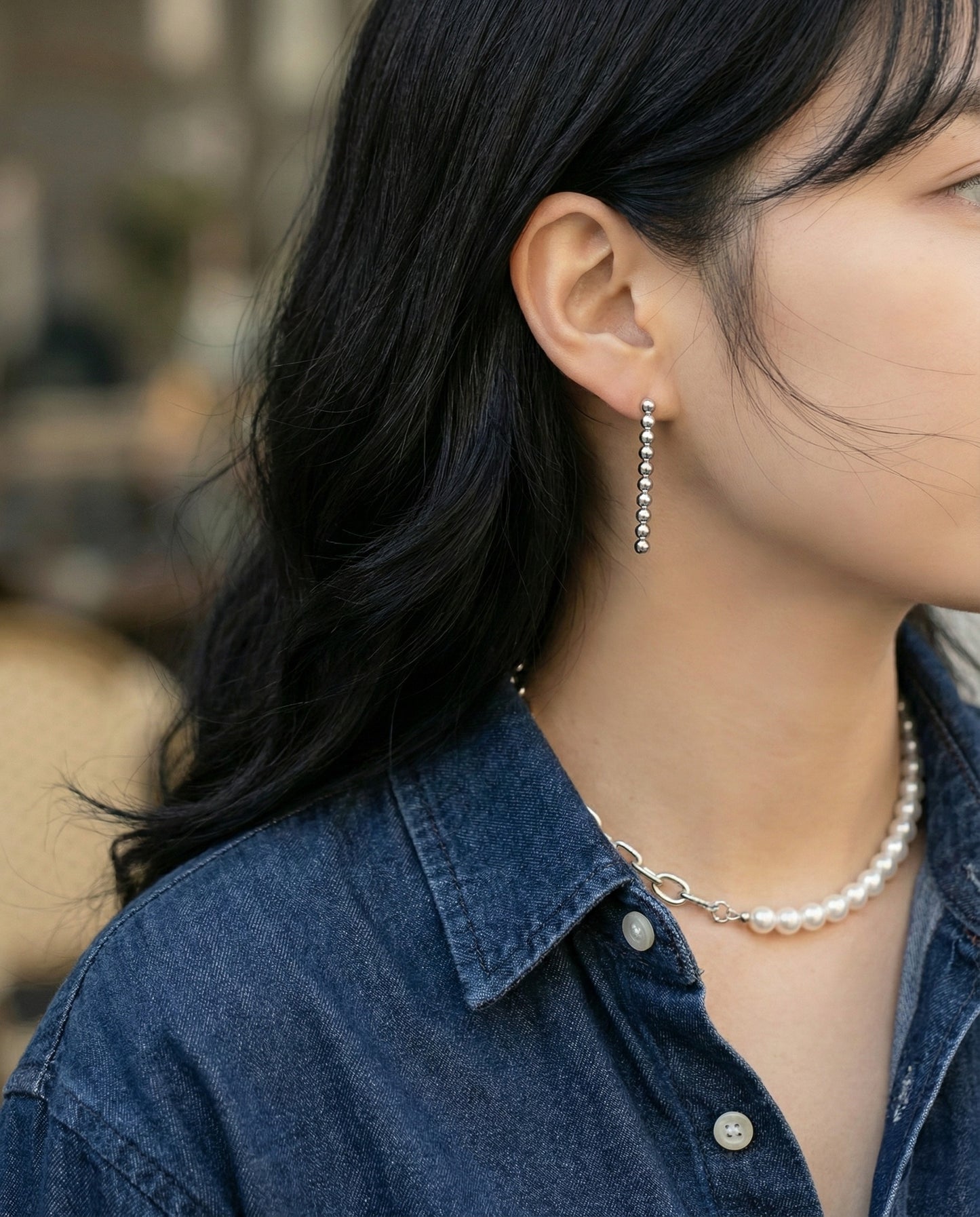 Woman in denim shirt wearing silver ball earrings with pearl necklace - professional look