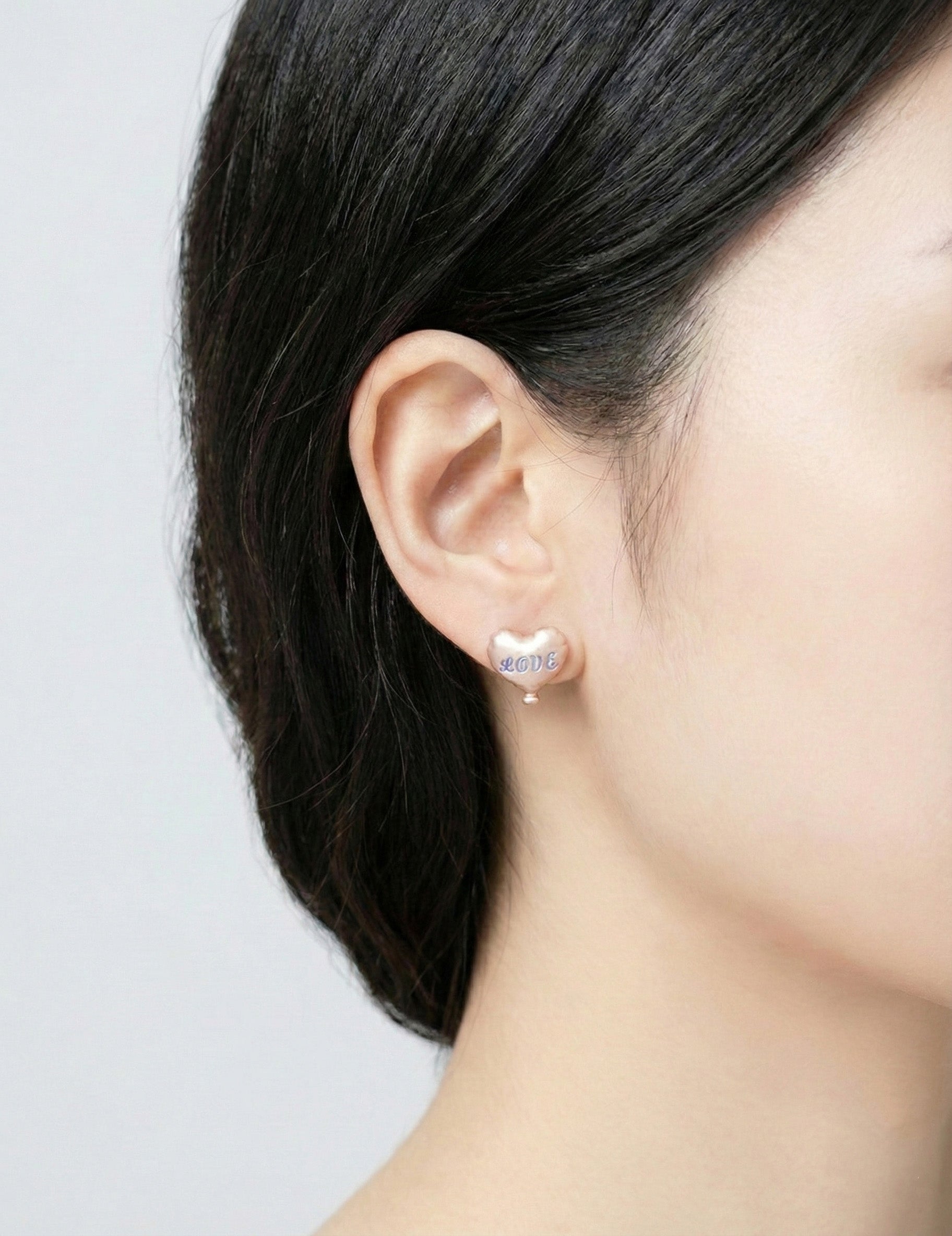 Side angle of woman wearing champagne beige heart balloon earring