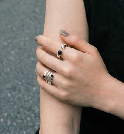 Model crossing arms wearing black onyx sterling silver open rings on both hands — black outfit close-up