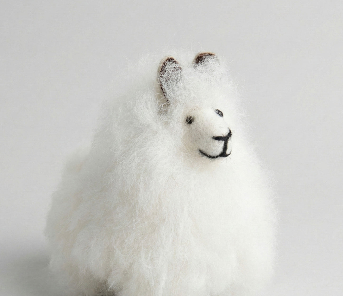 Close-up of white alpaca keychain showing detailed embroidered face