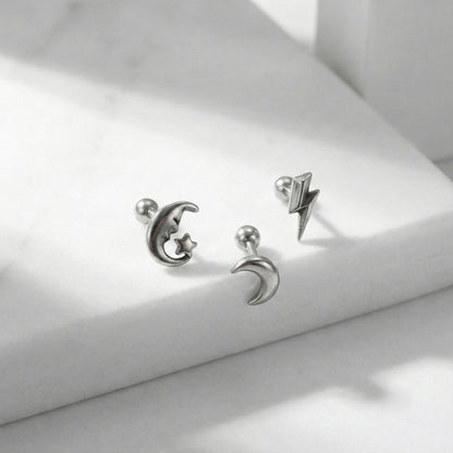 Detail shot of surgical steel celestial barbell studs with shadow - moon, crescent, lightning
