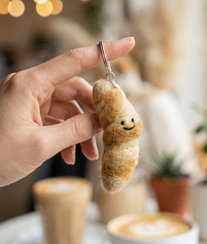 Hand holding handmade Nepal wool felt croissant keychain showing flaky texture details