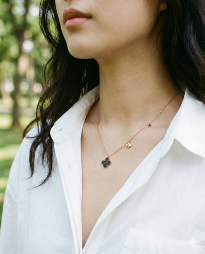 Woman wearing 925 silver cognac clover necklace over white open-collar shirt outdoors – asymmetric charm detail on rose gold chain