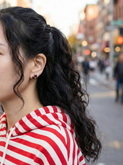 Street style photo of woman wearing Mickey Mouse black crystal earring with red and white striped shirt