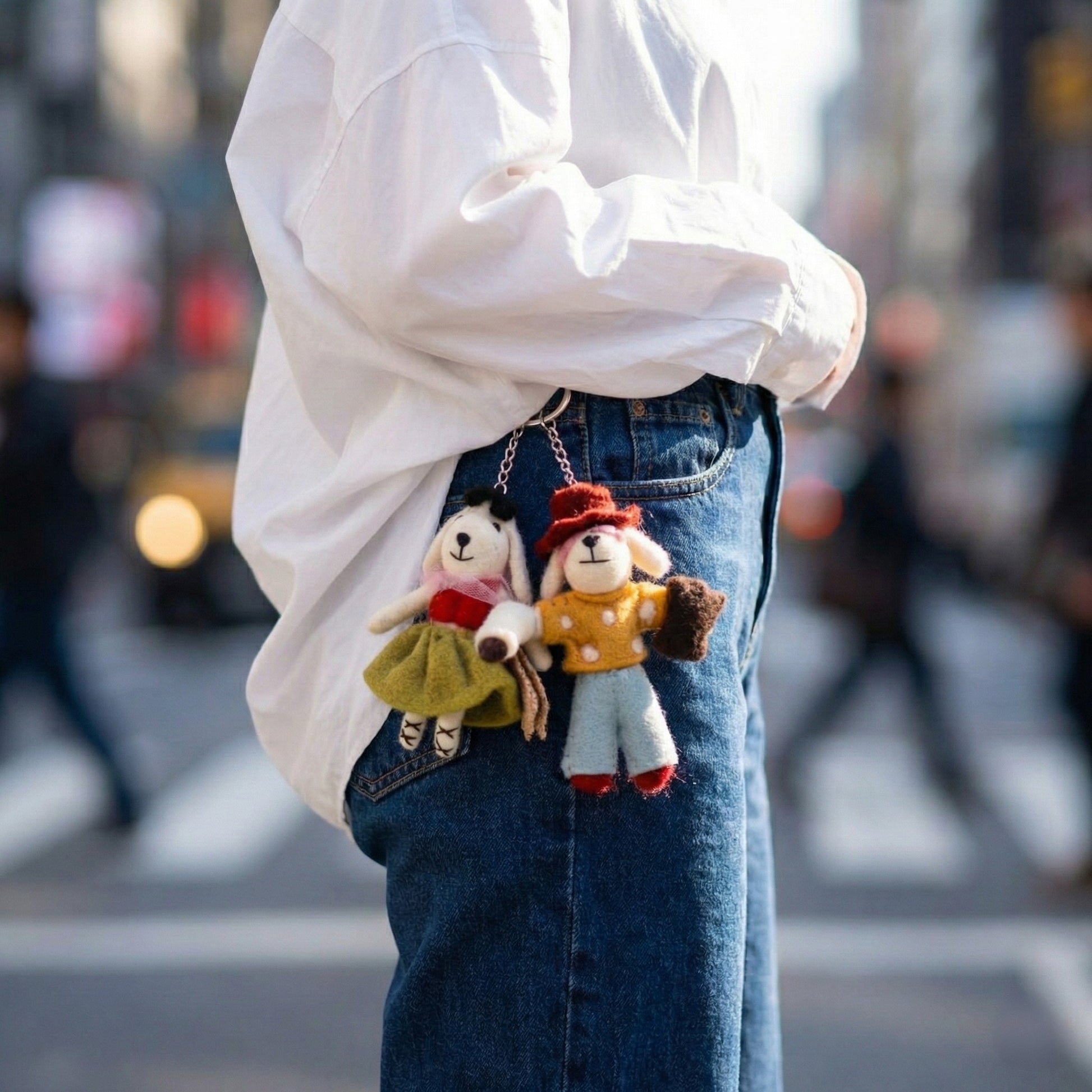 Felt keychains clipped to denim jeans belt loop - streetwear fashion accessory styling