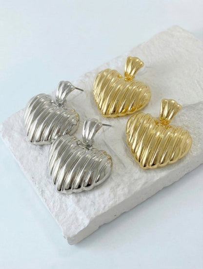 Pair of silver textured heart stud earrings displayed on clear acrylic stand