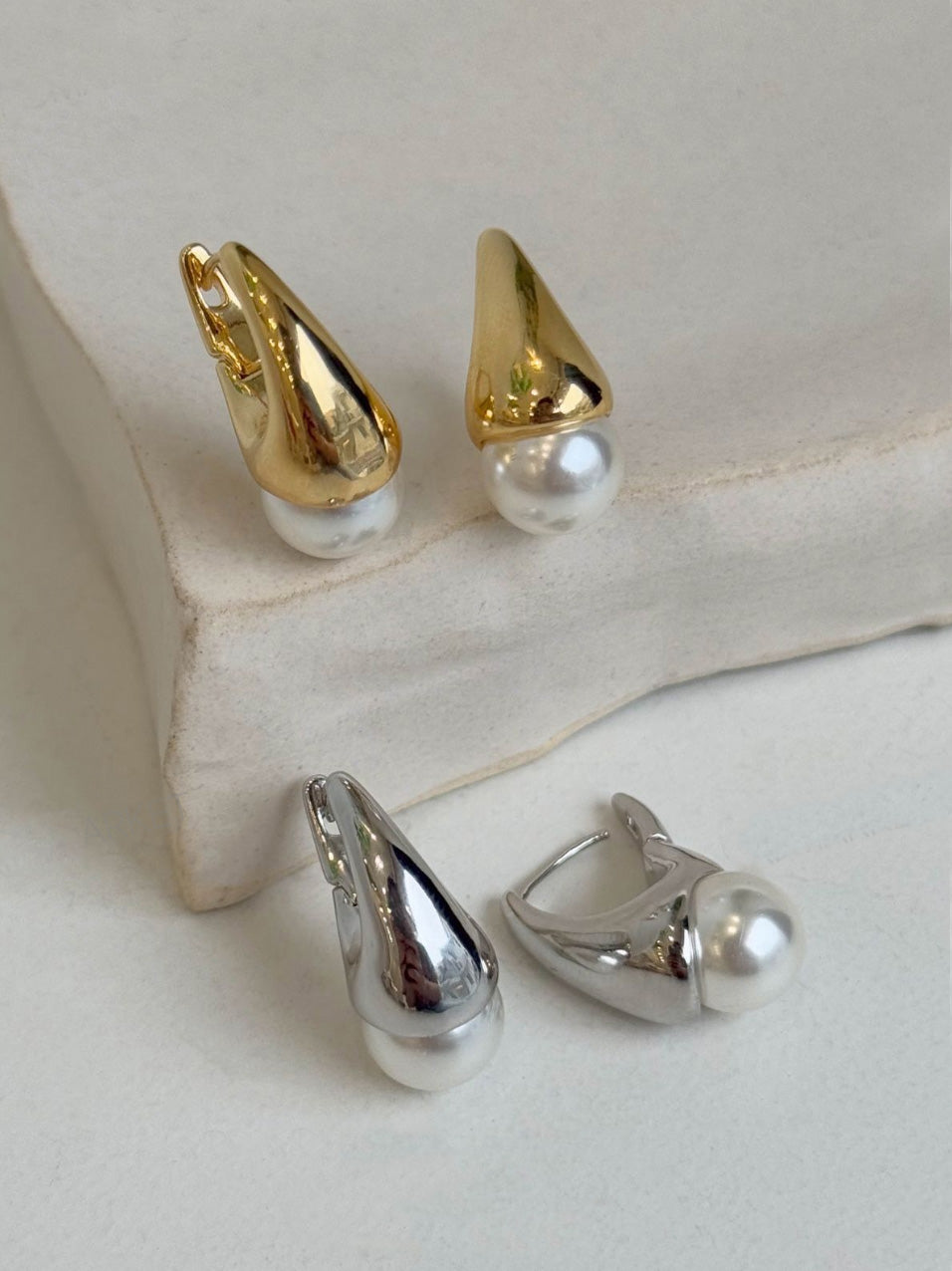  Gold and silver teardrop pearl huggie earrings set displayed on white stone background