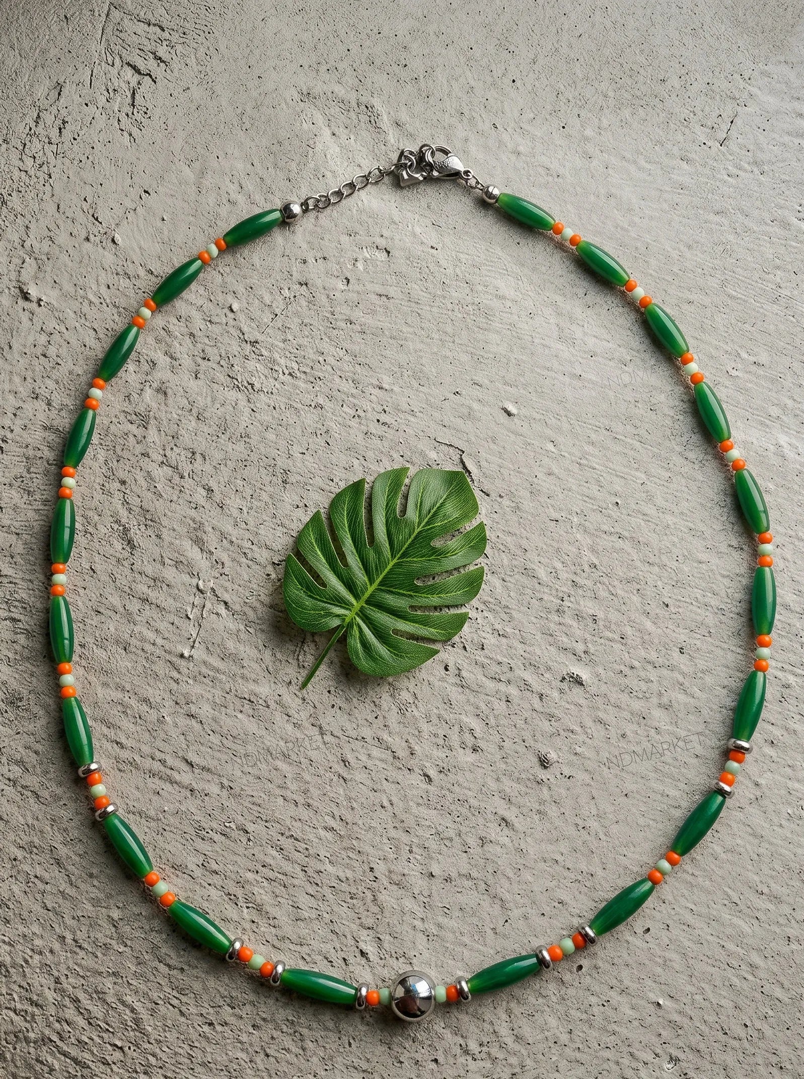 Botanical green single-strand beaded necklace with silver accent, resort wear aesthetic.