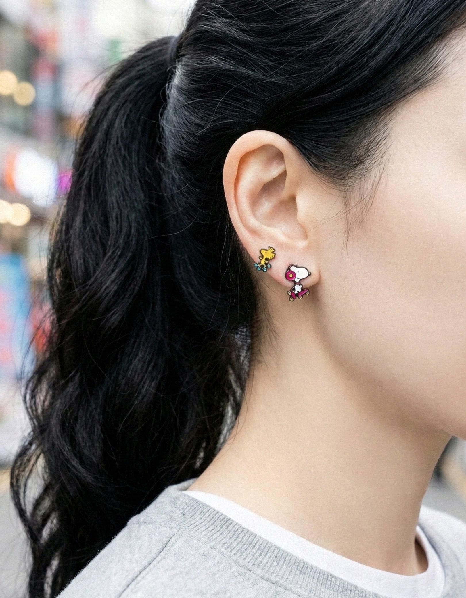 Outdoor lifestyle shot showing Snoopy ear jacket and Woodstock earring set worn together