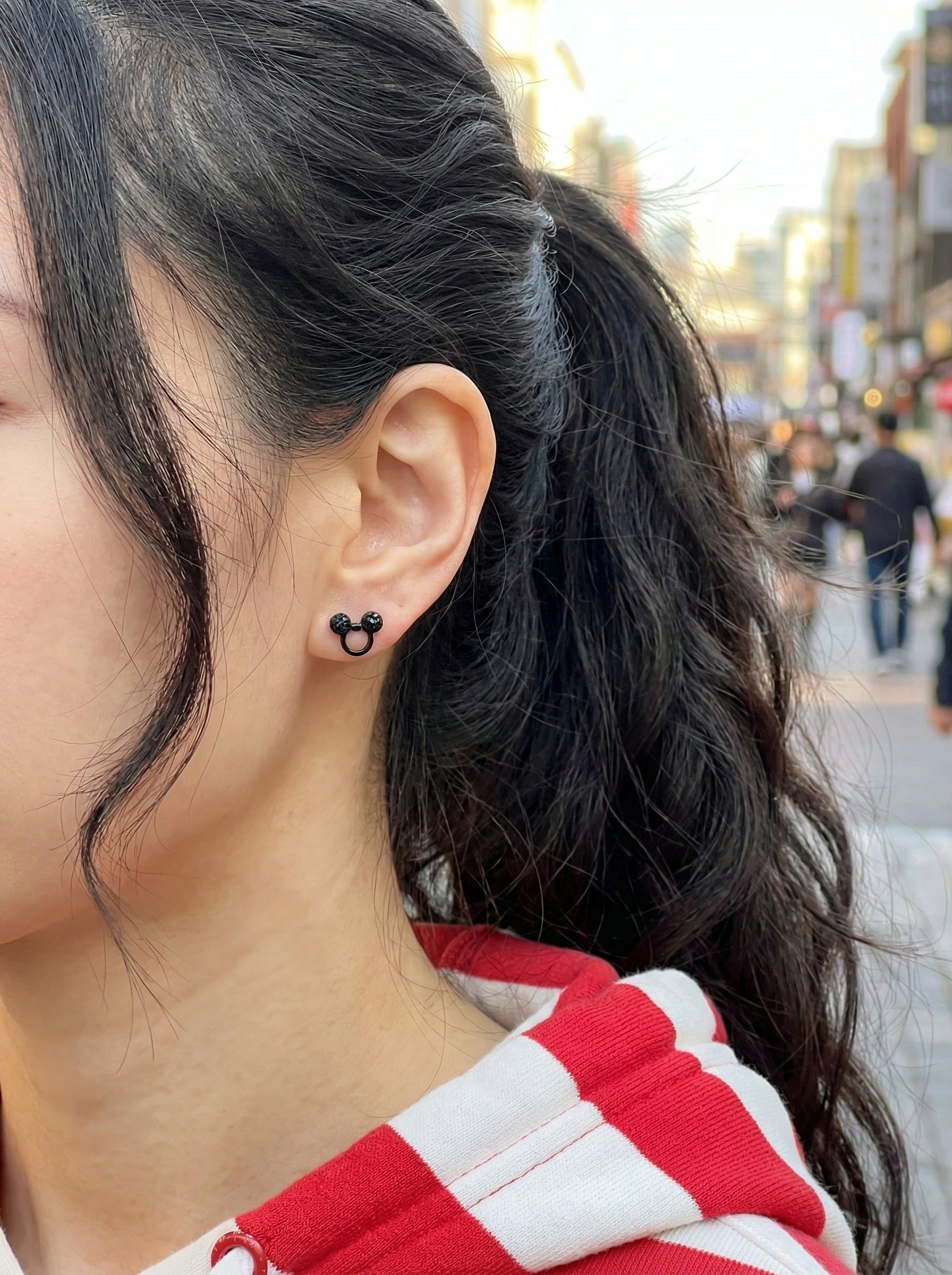 Street style photo of woman wearing Mickey Mouse black crystal earring with red and white striped shirt