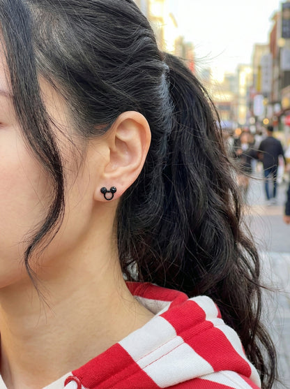 Street style photo of woman wearing Mickey Mouse black crystal earring with red and white striped shirt