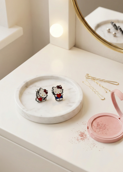 Hello Kitty studs displayed on vanity tray with gold hair pins and makeup, aesthetic kawaii lifestyle flatlay
