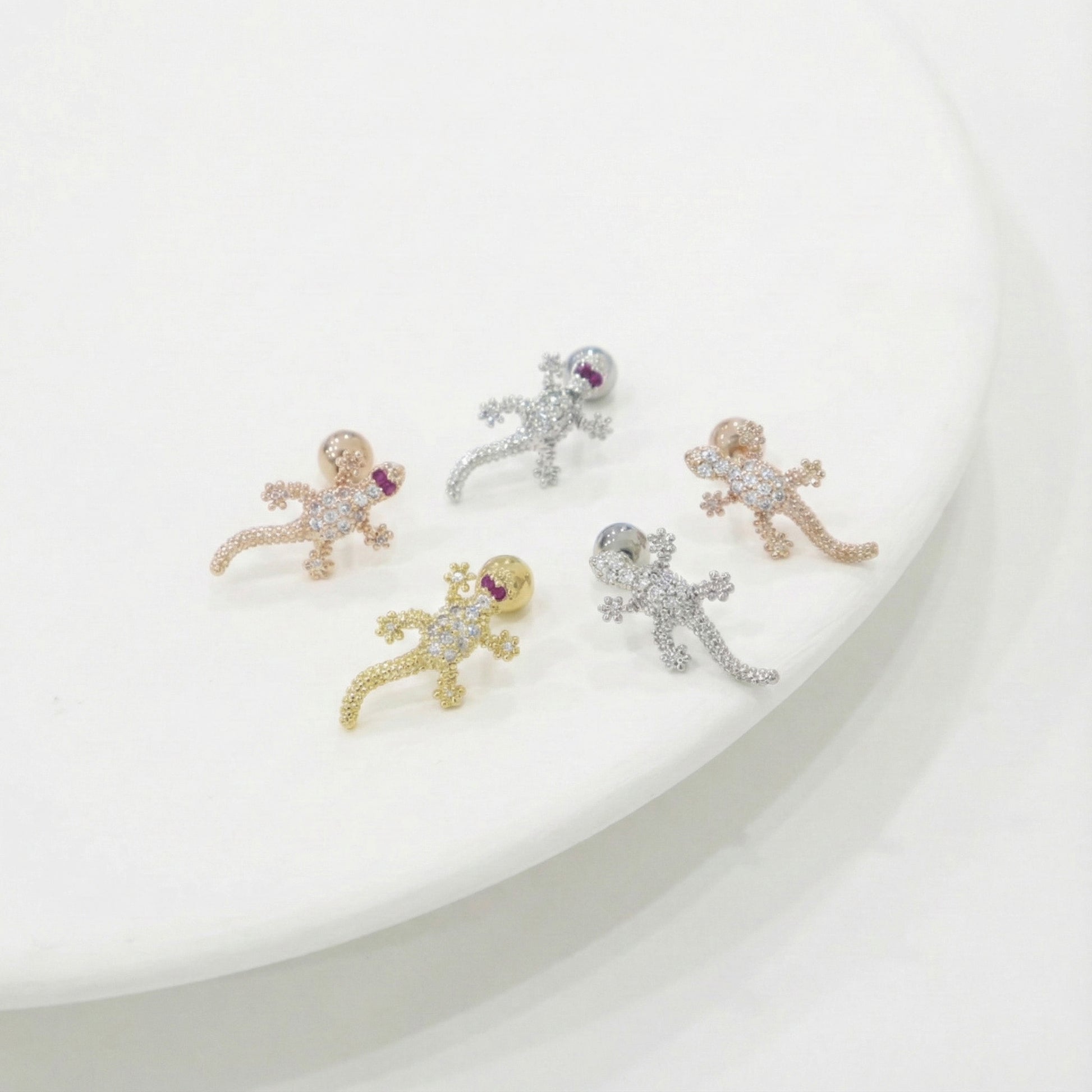 Five small animal-shaped earrings on a white plate