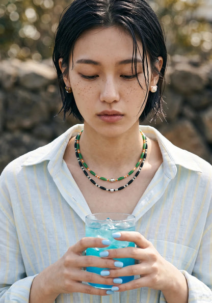Vacation outfit inspo green and black beaded necklace stack, K-style summer jewelry.