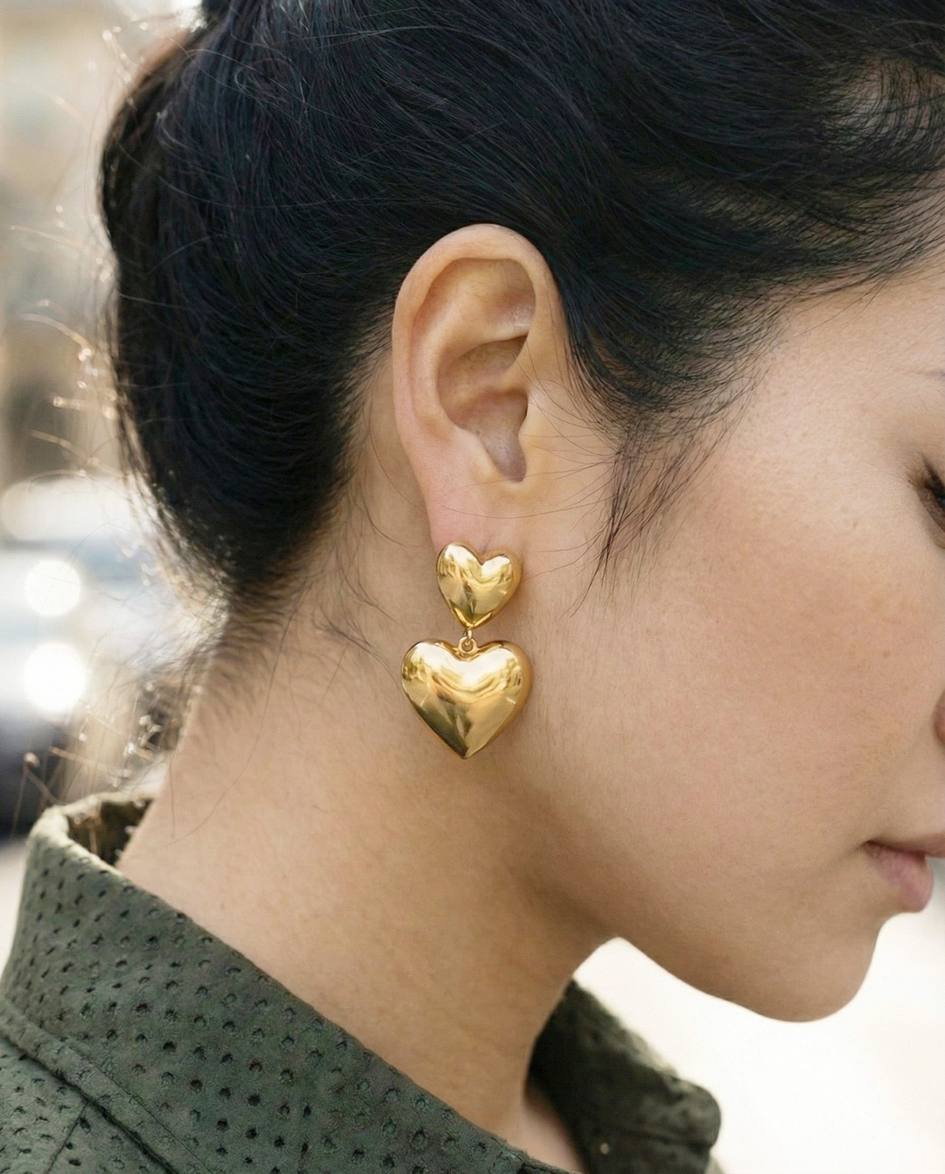 Gold chunky heart earrings with green textured jacket - street style close-up