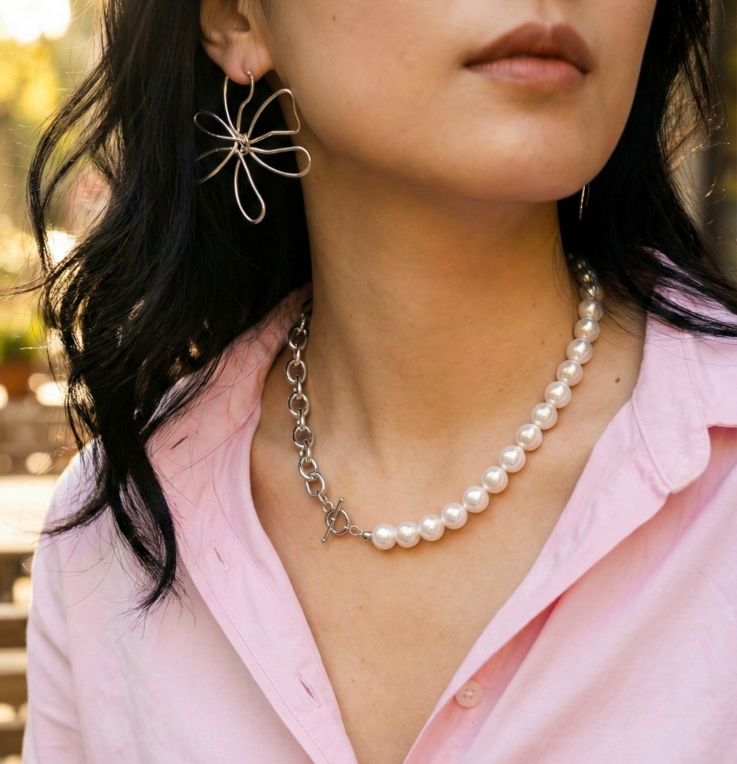 Woman in pink shirt wearing mixed media pearl and chain statement necklace with flower earrings