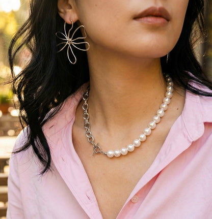 Woman in pink shirt wearing mixed media pearl and chain statement necklace with flower earrings