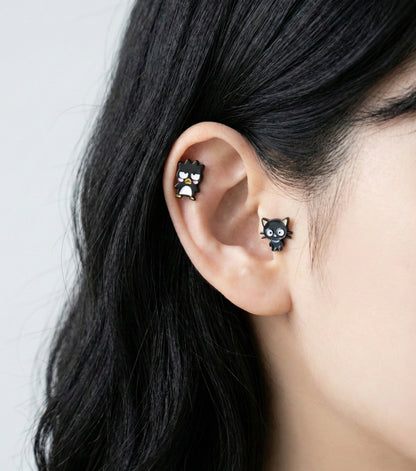 Sanrio character studs layered on ear cartilage - Badtz-Maru on helix, Chococat on lobe piercing