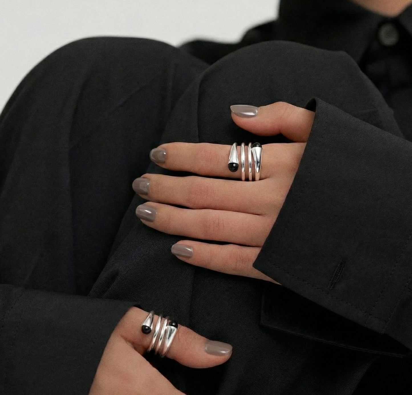  Editorial close-up of model in black blazer wearing 925 sterling silver spiral wrap ring — multiple fingers