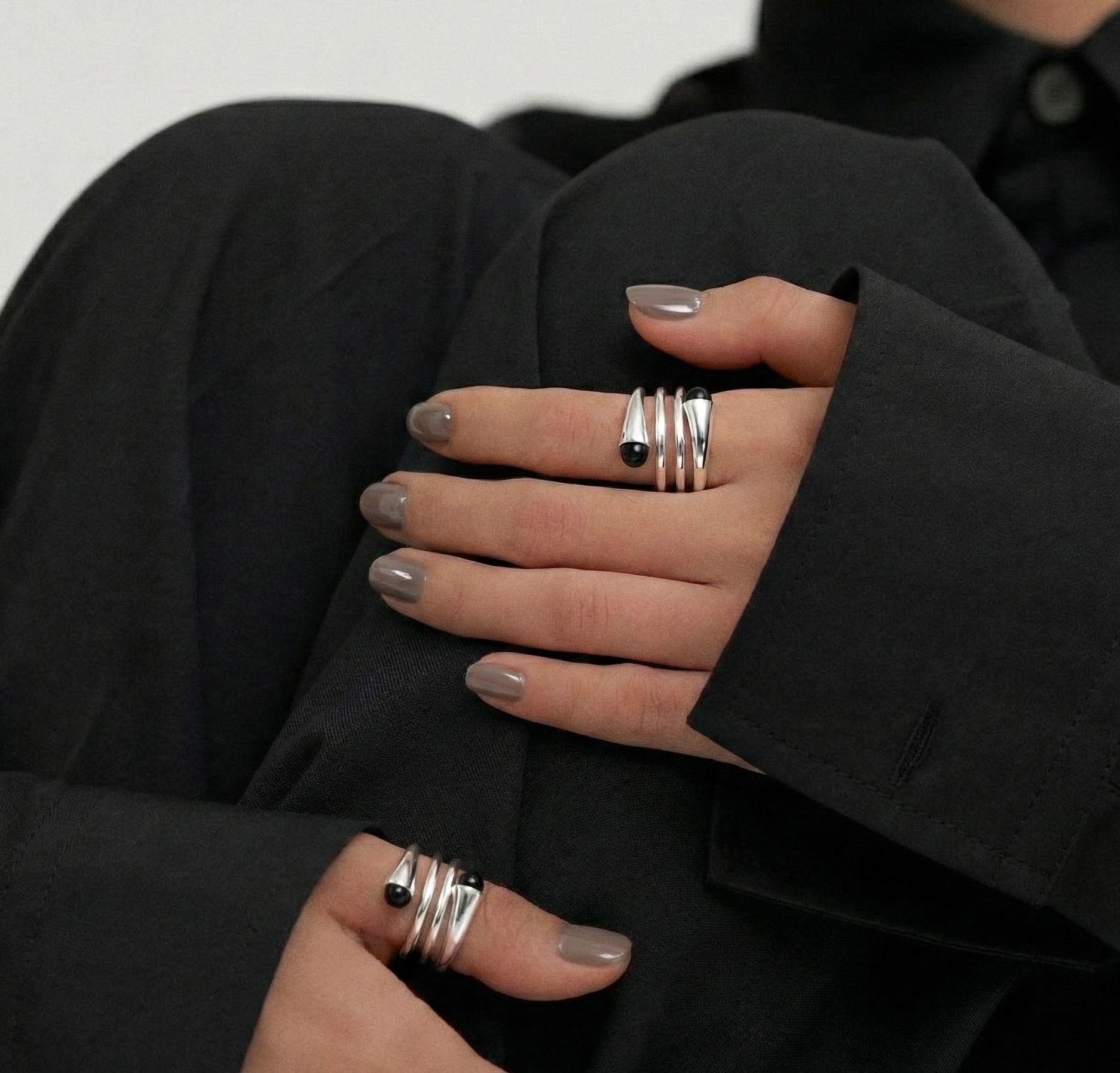  Editorial close-up of model in black blazer wearing 925 sterling silver spiral wrap ring — multiple fingers