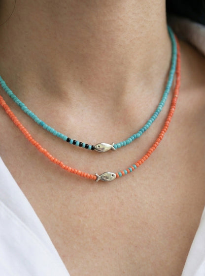 Layered mint turquoise and orange seed bead chokers worn with white blouse beach vacation style