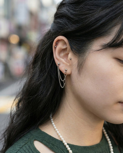 Double piercing chain earrings styled with pearl necklace showing versatile jewelry layering for Y2K aesthetic