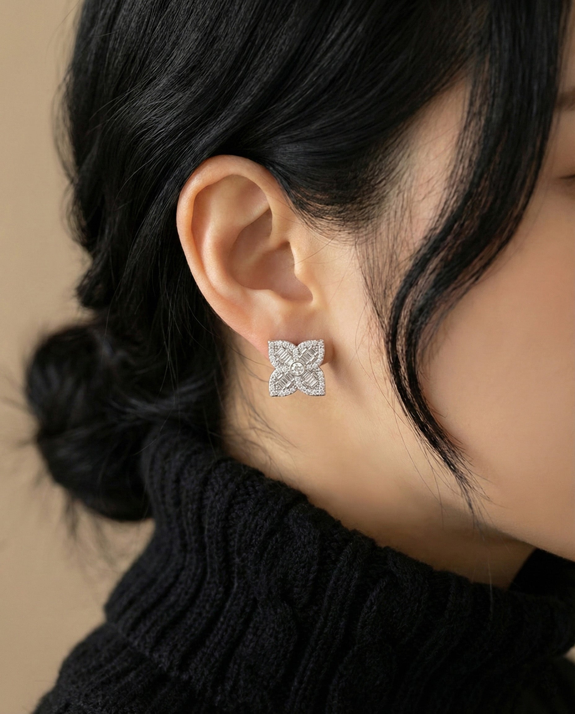 Silver baguette cut flower stud earrings on ear with black outfit styling