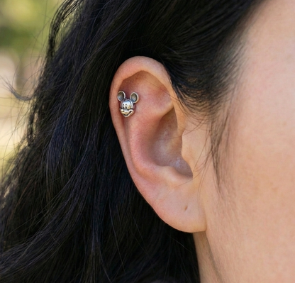 Single Mickey Mouse piercing worn on upper helix cartilage