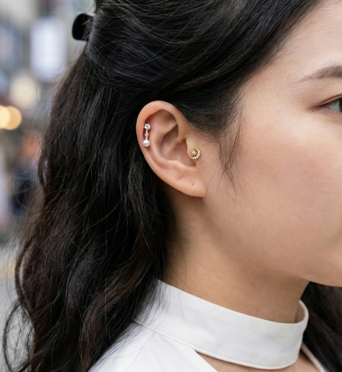 Layered ear piercings with moon star stud on conch and pearl drop on forward helix