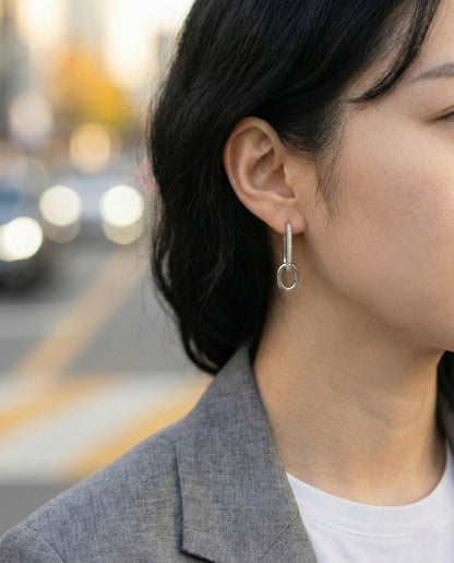 Woman wearing silver oval link drop earrings with gray blazer, office style