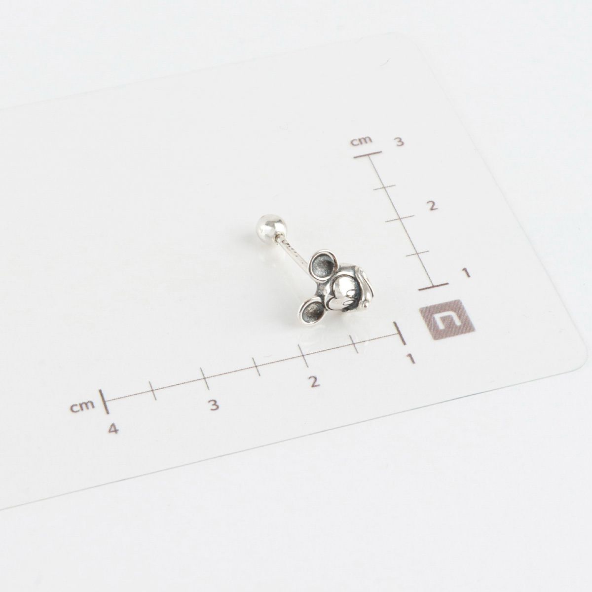 Size measurement of Mickey Mouse piercing with ruler showing dimensions