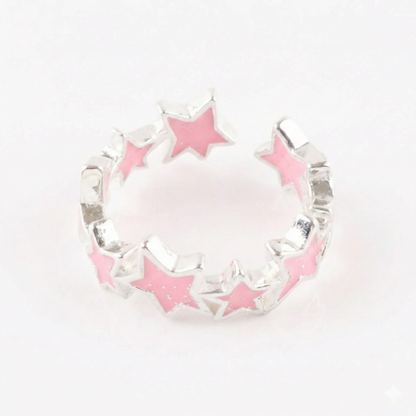 Baby pink sparkling star ring with glitter enamel on light wooden surface with book