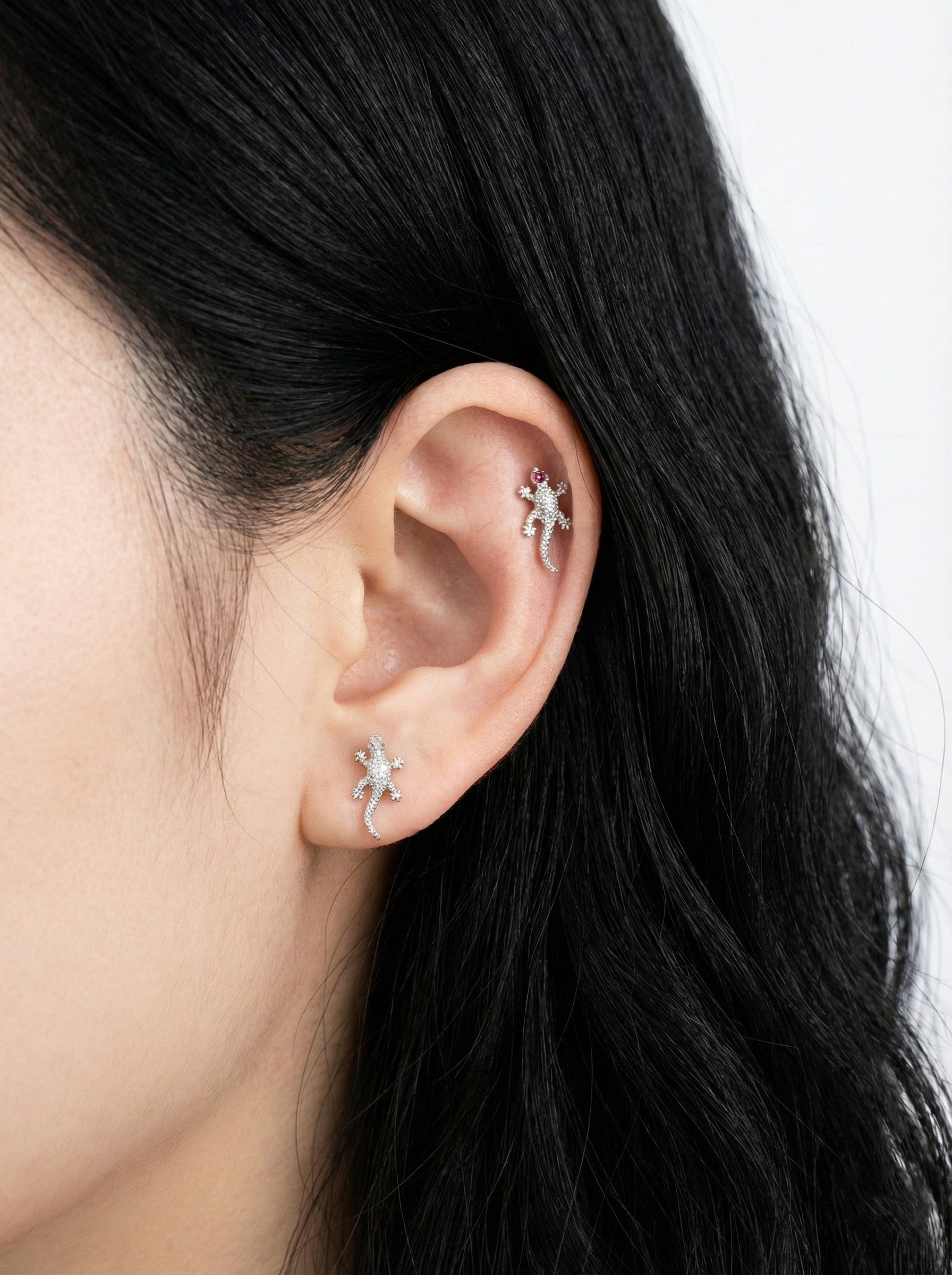 Close-up of an ear wearing two silver star-shaped earrings with a blurred background.