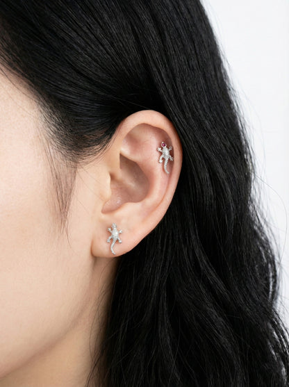 Close-up of an ear wearing two silver star-shaped earrings with a blurred background.
