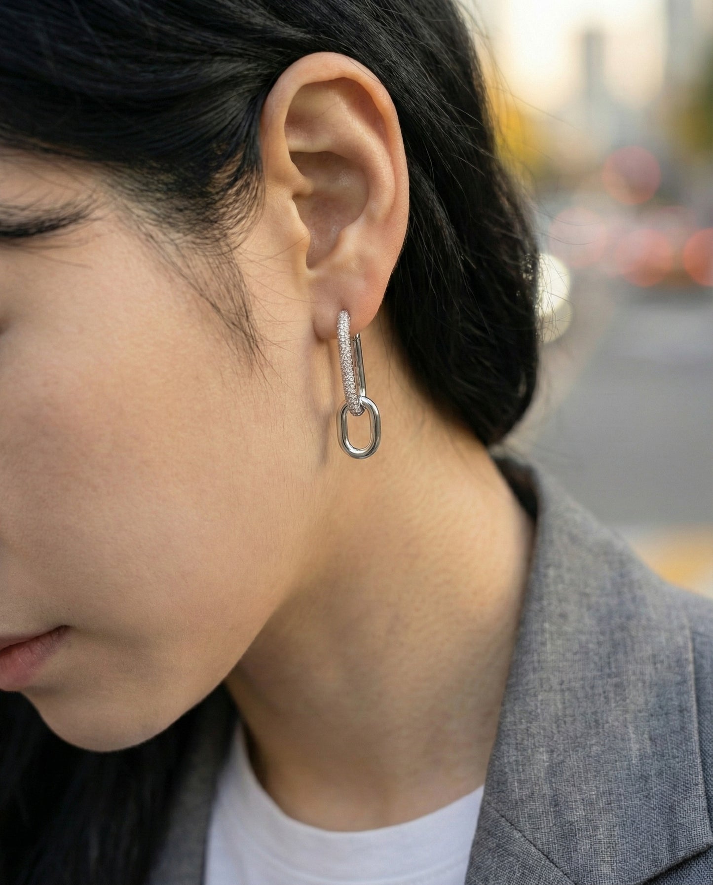 Outdoor shot of woman wearing silver oval link drop earrings, top pave design