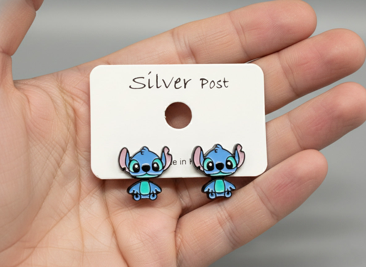 Hand holding silver post card with blue alien 2-way ear jacket earrings showing size comparison