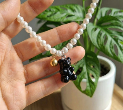 Hand holding black gummy bear pearl necklace with gold accent showing detail