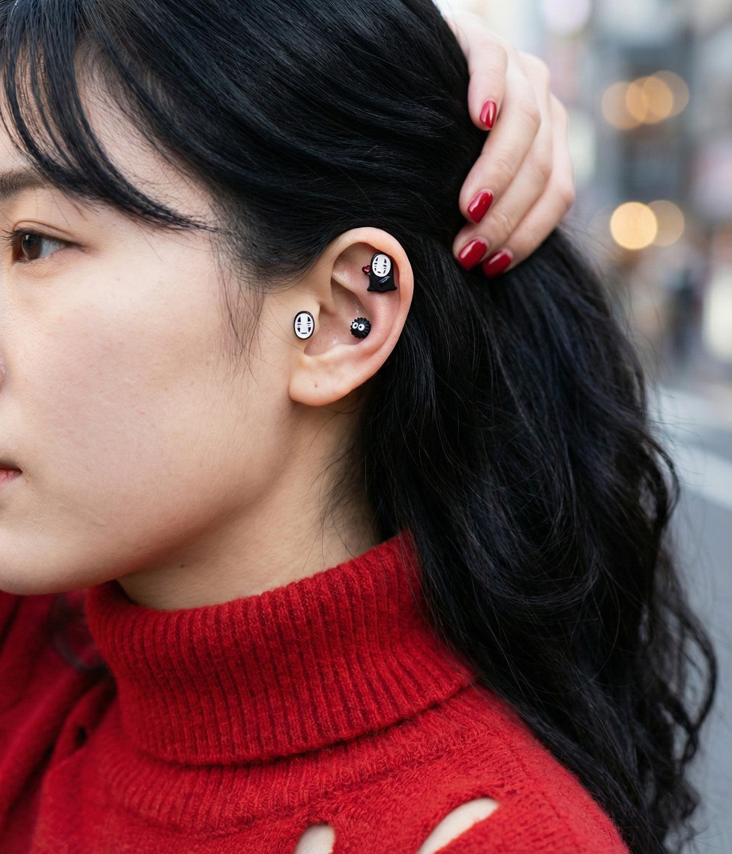 Three handmade No-Face Kaonashi stud earrings displayed on an open book under warm lamp light with aesthetic vintage styling.