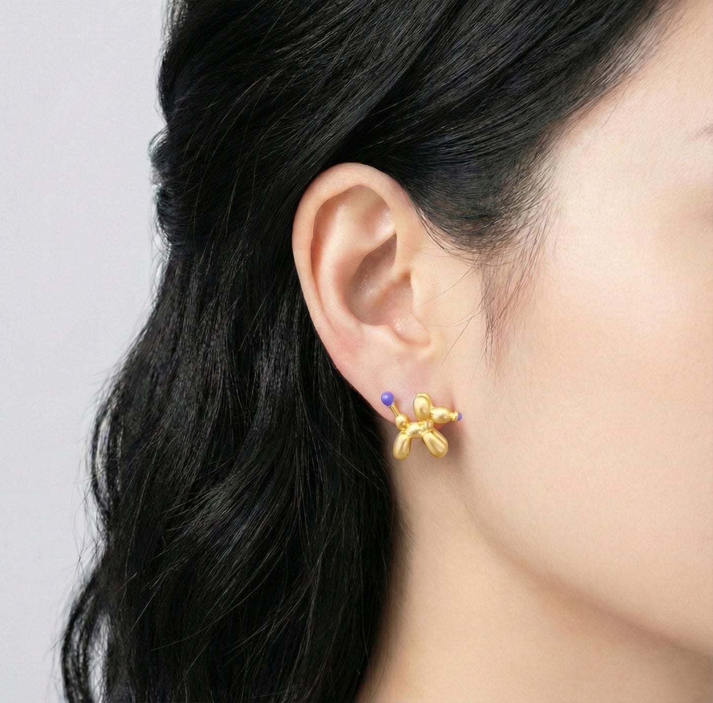 Model wearing gold purple balloon dog earring showing luxury pop art aesthetic