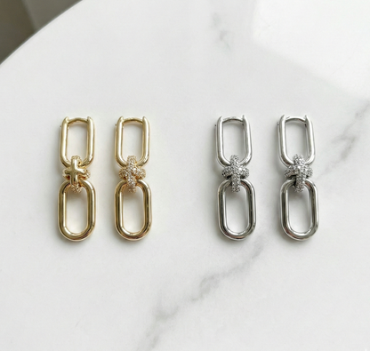Gold and silver chain knot earrings side by side comparison on white marble surface