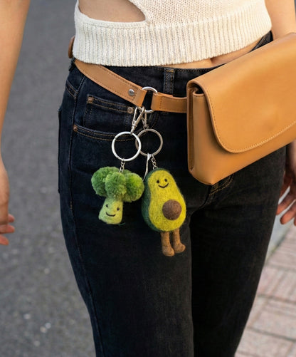 Bag strap styled with broccoli and avocado keychains for street fashion look