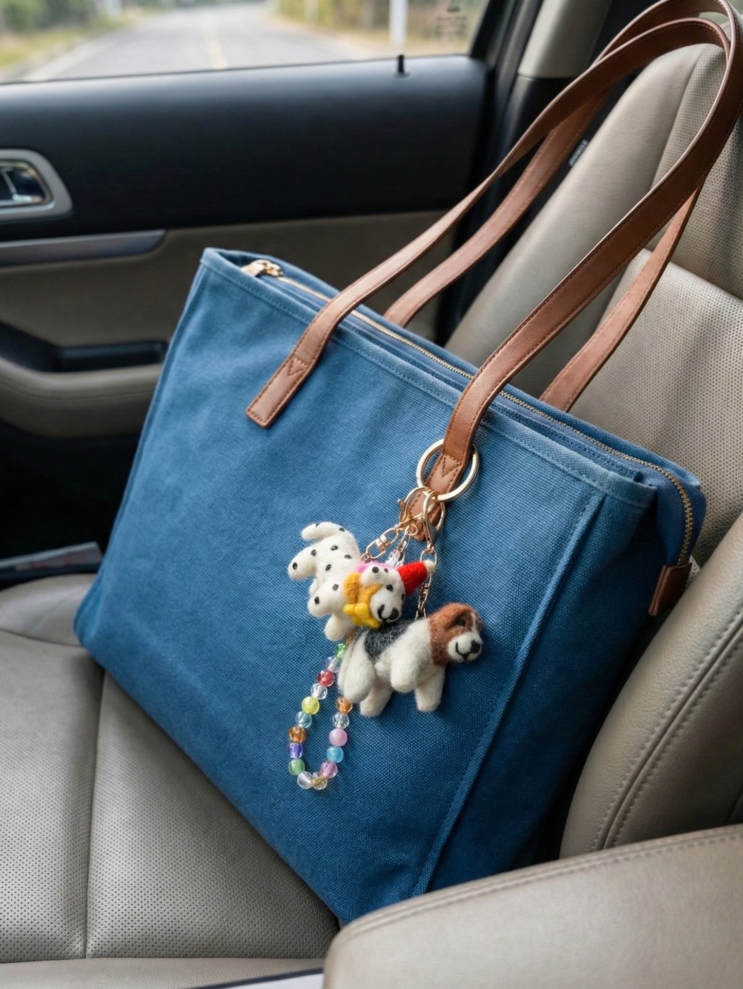 Blue canvas tote bag in car with handmade felt dog keychains and colorful bead accents