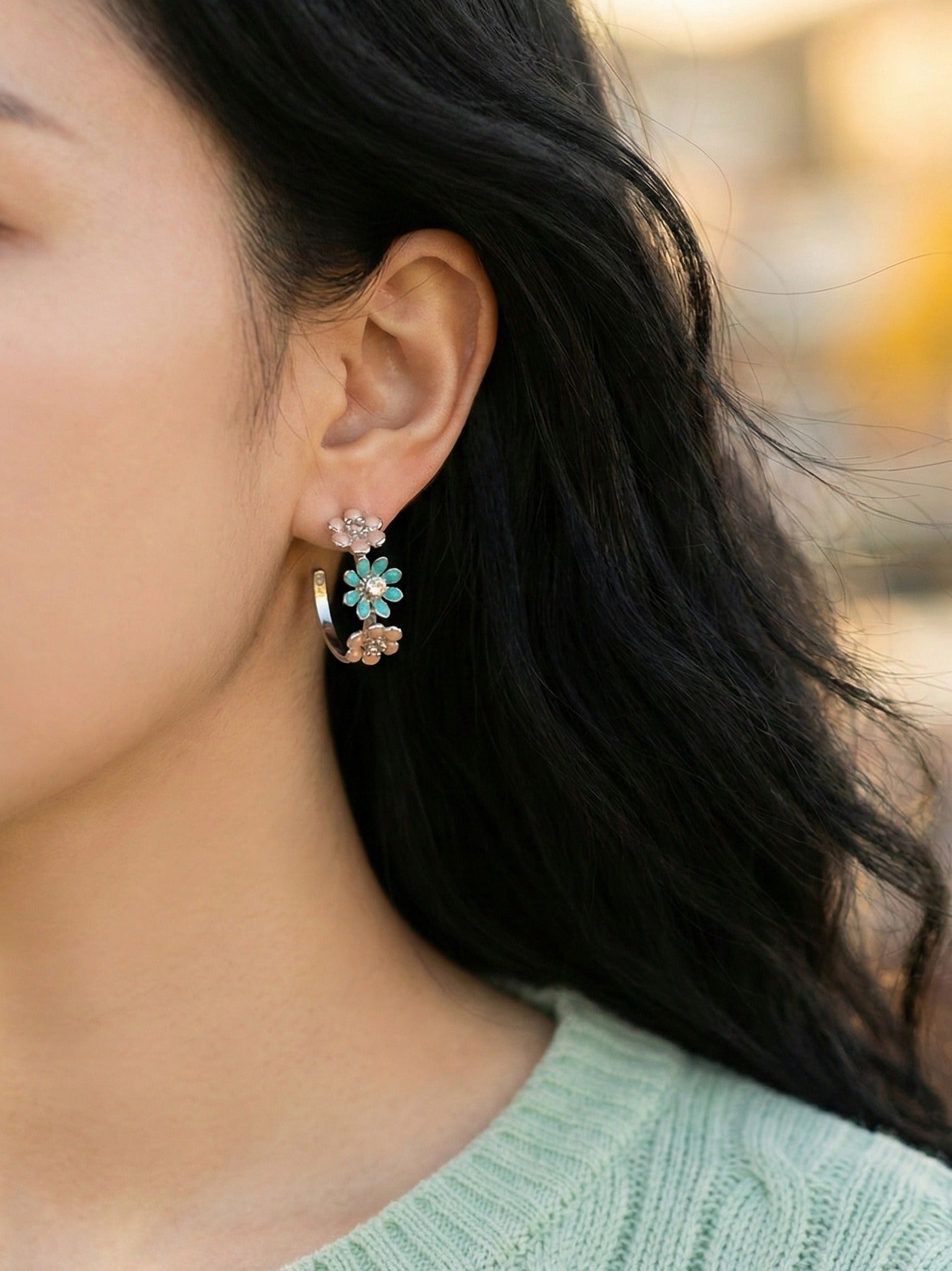 Side view of model wearing peach blossom enamel flower hoop earrings with natural lighting