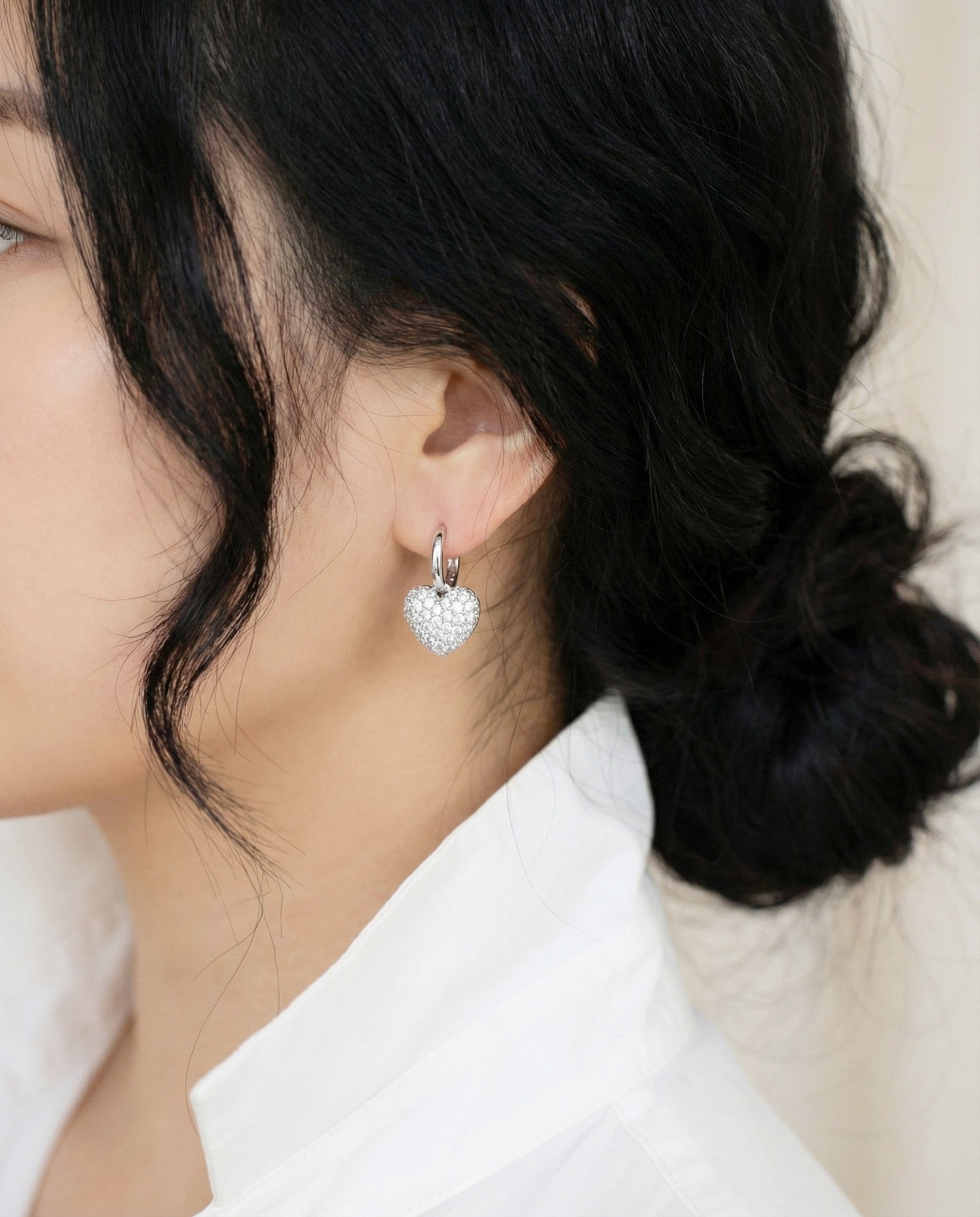Profile shot of silver pave heart earrings on model showing comfortable fit