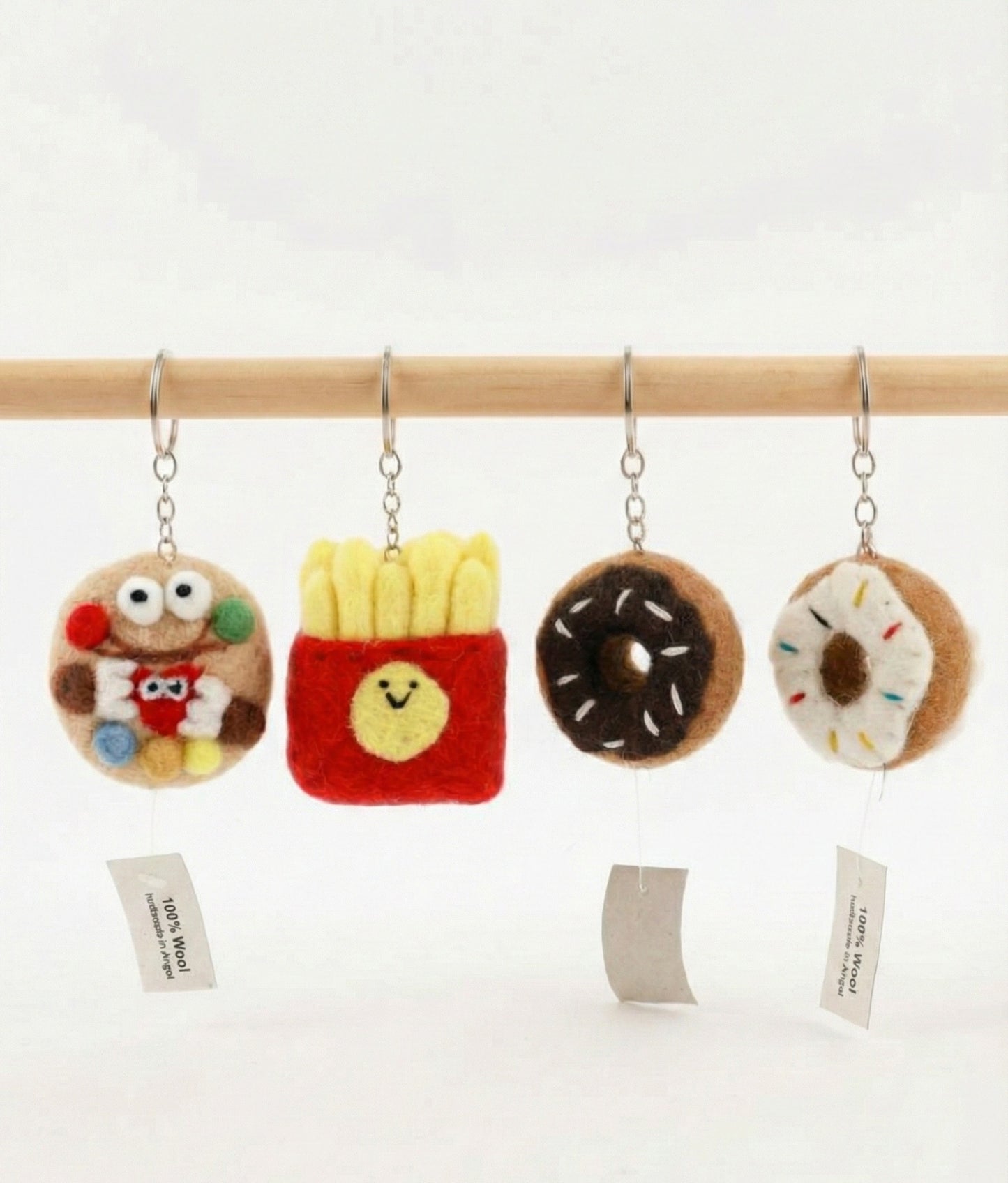 Four wool felt food keychains hanging on wooden rod with handmade in Nepal tags visible